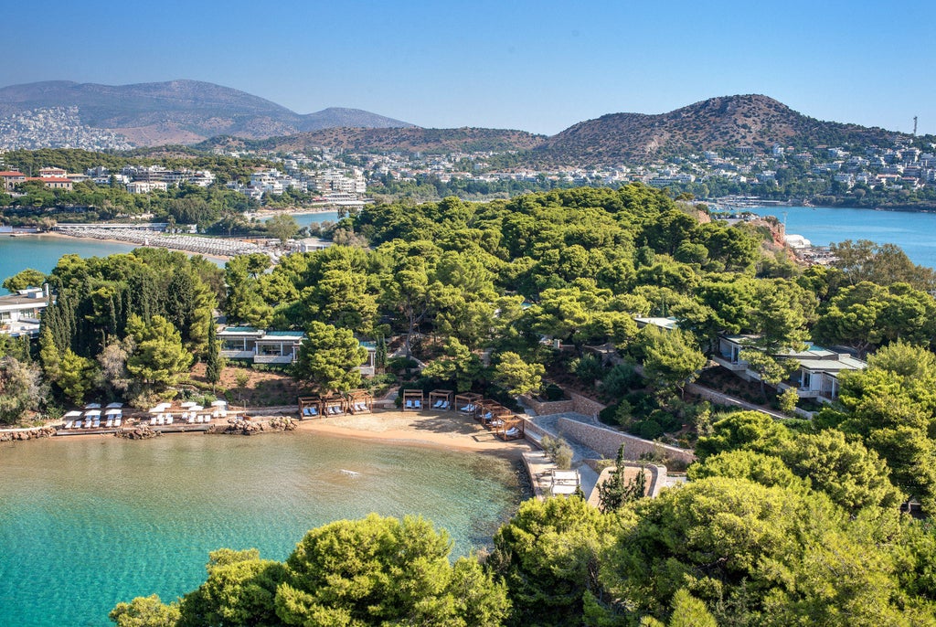 Luxury seaside hotel in Athens with white buildings cascading down hillside, infinity pools overlooking azure Mediterranean waters