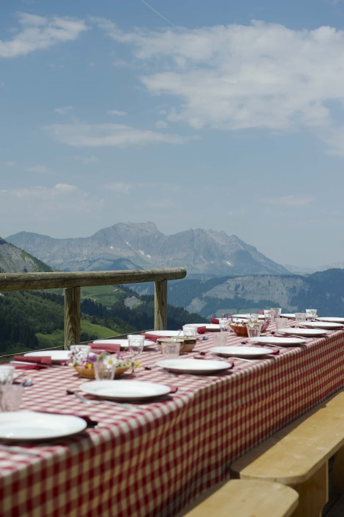 Elegant French mountain lodge with rustic wooden exterior, nestled in alpine landscape, featuring warm lighting and luxurious chalet-style architecture