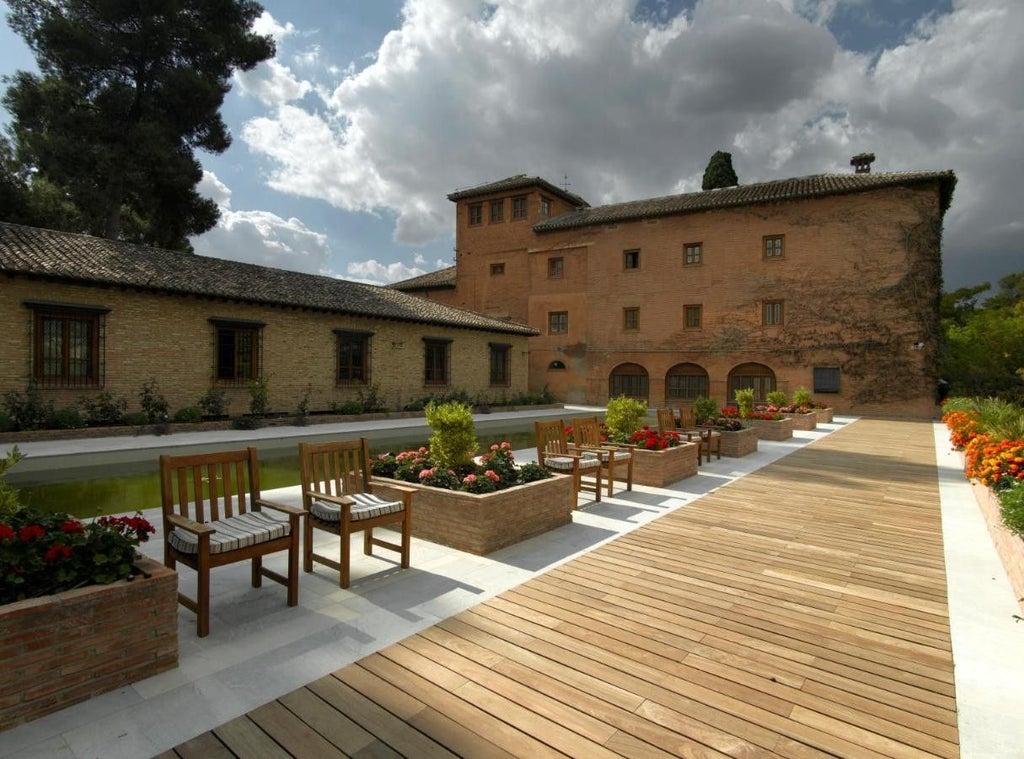 Historic luxury hotel Parador Granada with stone facade, arched windows and Moorish architecture nestled against Alhambra Palace grounds