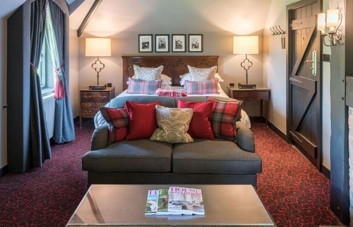 Elegant cottage duplex suite at The Lygon Arms, featuring plush bedding, refined wood furnishings, and warm neutral tones in a classic British hospitality setting