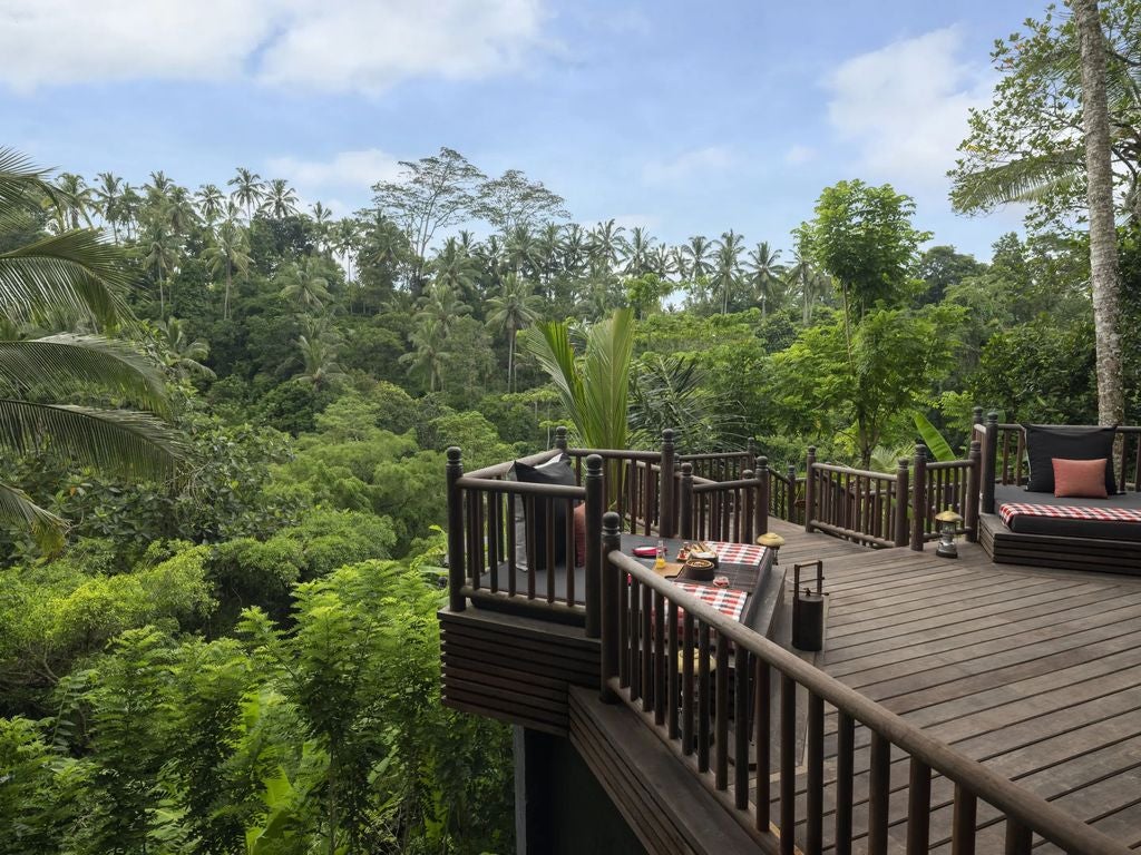 Modern luxury hotel exterior with curved glass facades, surrounded by lush tropical gardens and illuminated by warm evening lighting