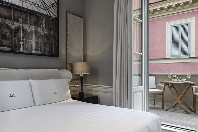 Elegant Grand Deluxe Room at J.K. Place Roma with plush cream upholstered headboard, soft neutral tones, and sophisticated Italian design details