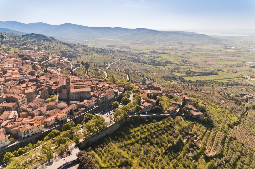 Rolling green hills dotted with cypress trees and rustic villas, overlooking a sun-drenched Tuscan valley with vineyard rows at sunset