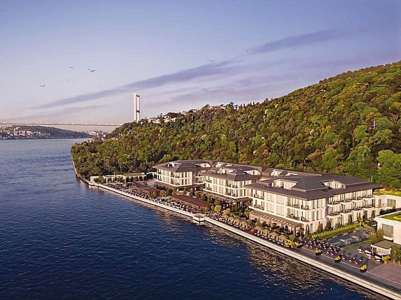 Luxurious modern hotel overlooking Bosphorus strait, featuring sleek architectural design with floor-to-ceiling windows and elegant waterfront terrace at sunset