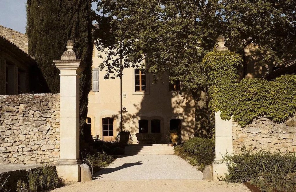 Elegant stone facade of Le Galinier hotel in Provence, featuring soft golden limestone, lavender-lined pathway, and traditional French architectural charm