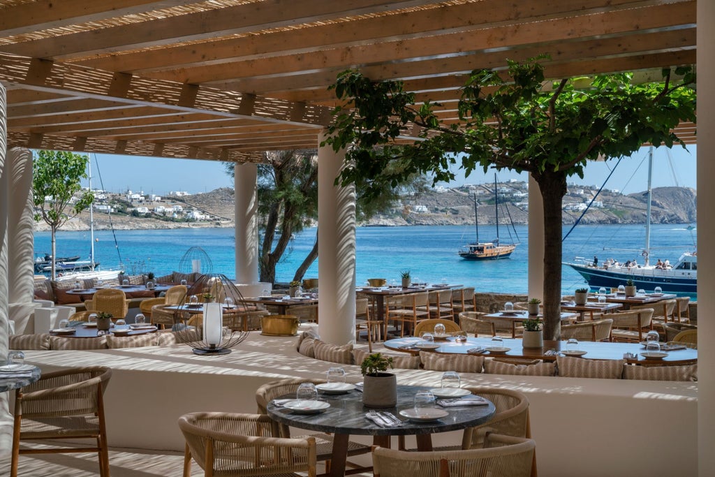 Elegant infinity pool overlooking the Aegean Sea at sunset, with white lounge chairs and minimalist Greek architecture in Mykonos