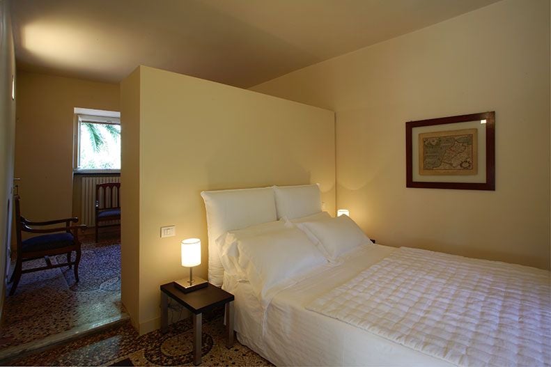 Elegant Italian garden-view hotel room with soft neutral tones, luxurious white linens, and delicate rosemary-inspired decor at Villa Rosmarino