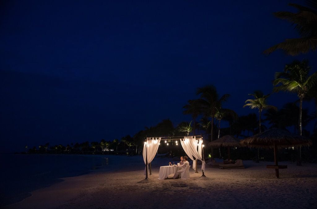 Luxurious beachfront resort with pristine white sand, turquoise waters, and elegant Caribbean-style villas nestled among lush tropical greenery in Antigua.