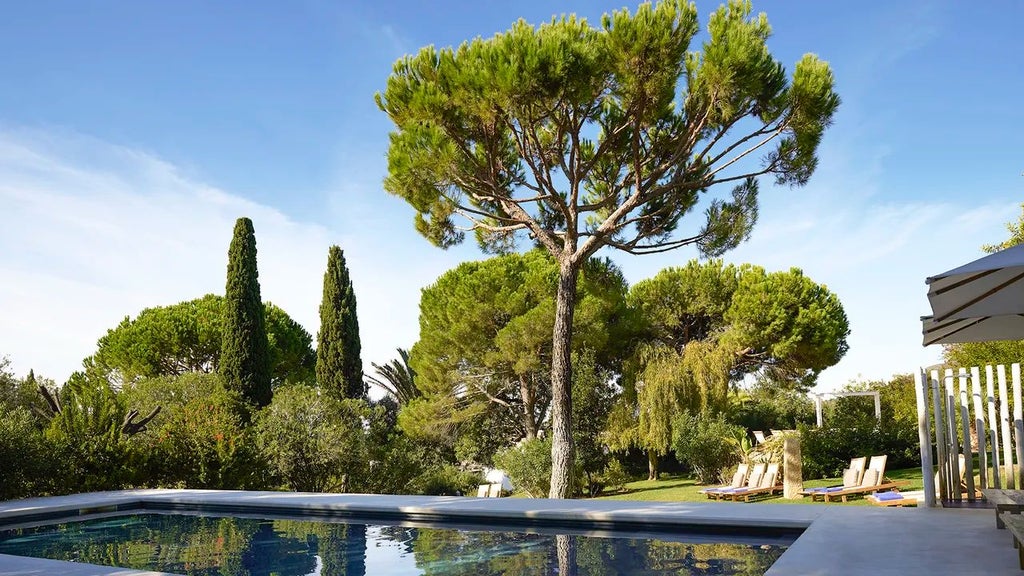 Whitewashed Portuguese villa with terracotta roof, surrounded by lush gardens, elegant pool, and traditional Algarve architecture at sunset