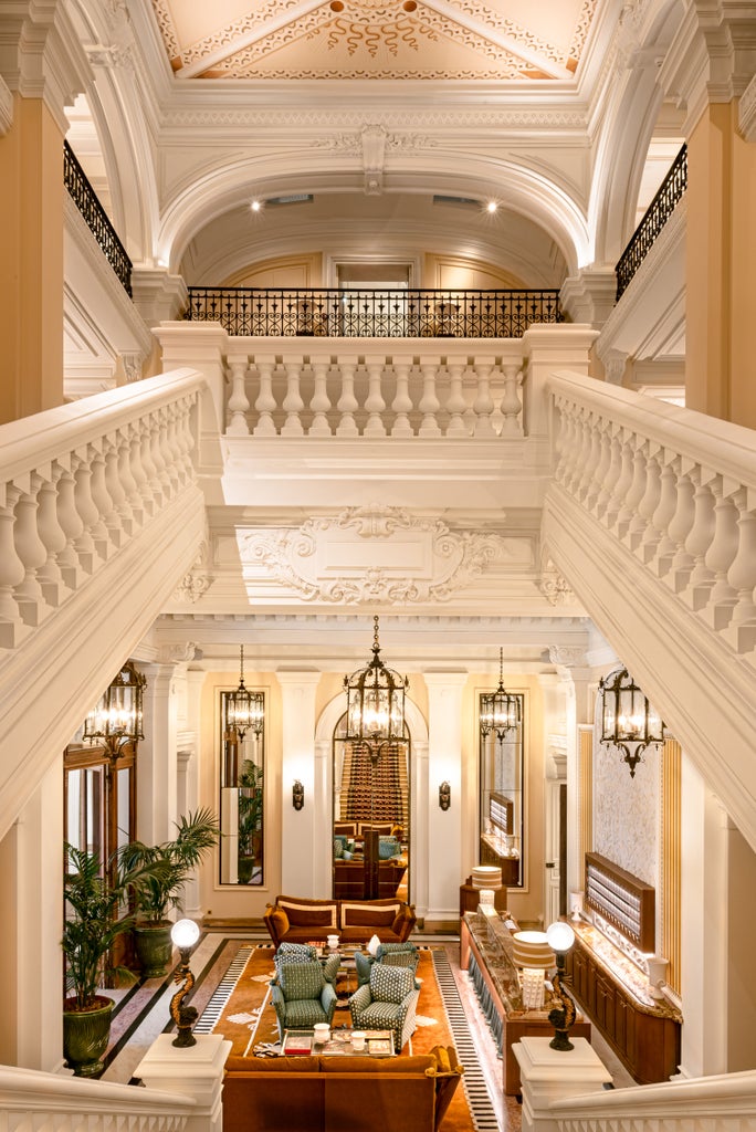 Ornate 19th-century Parisian mansion hotel with red-and-white striped awnings, elegant balconies, and manicured garden entrance