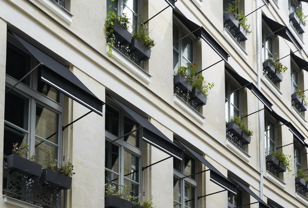 Elegant boutique hotel facade with soft beige exterior, ornate French windows, and sleek modern design highlighting Parisian luxury hospitality aesthetic