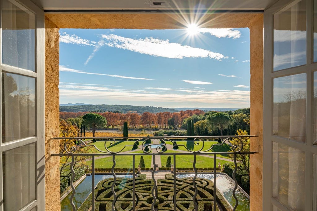 Elegant French château nestled in lush Provençal landscape, featuring stone architecture, manicured gardens, and golden sunlight casting a warm glow