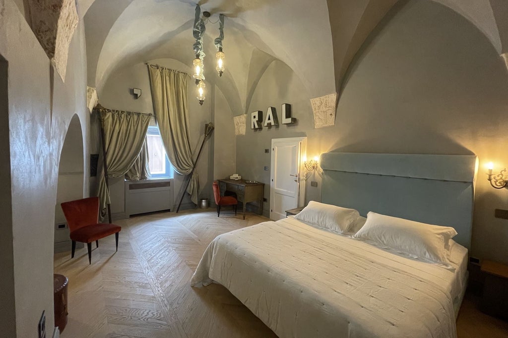 Elegant Baroque-style superior suite with plush white linens, ornate ceiling, antique furnishings, and soft natural light in a historic Italian hotel room