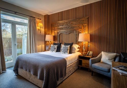 Elegant boutique hotel room with plush white bedding, soft lighting, and modern rustic decor in a charming countryside setting at Scenset House in the United Kingdom.