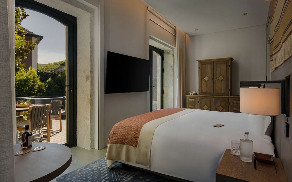 Luxurious valley-view hotel room with floor-to-ceiling windows, modern furnishings, freestanding bathtub, and plush king bed at Six Senses Douro