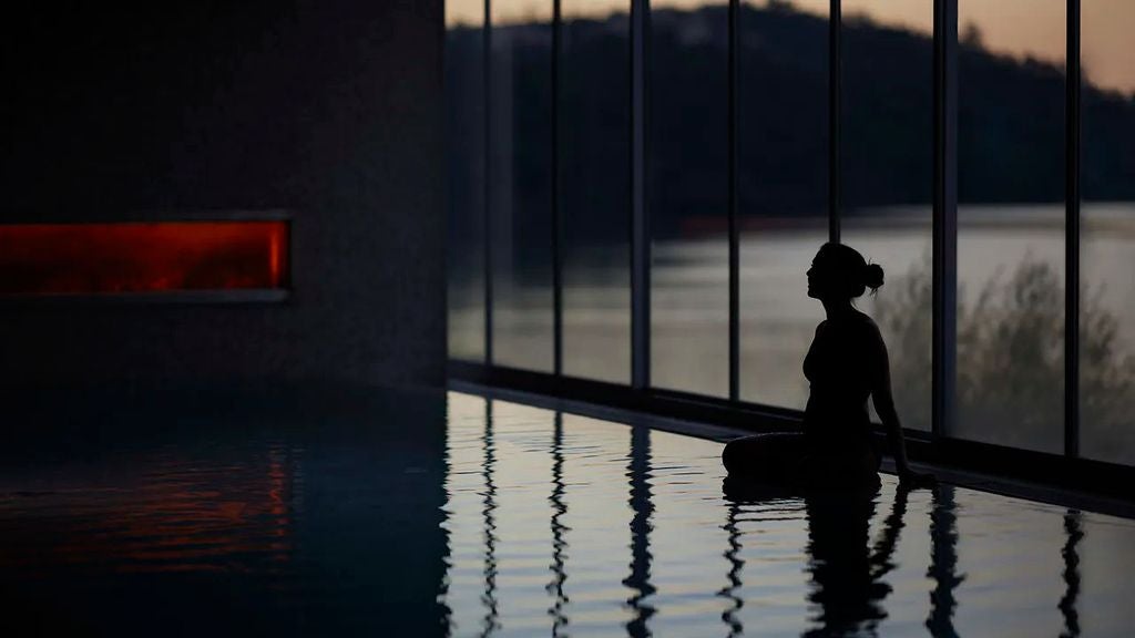 Scenic hillside luxury hotel overlooking Douro River valley, with infinity pool merging into terraced vineyards and misty mountains