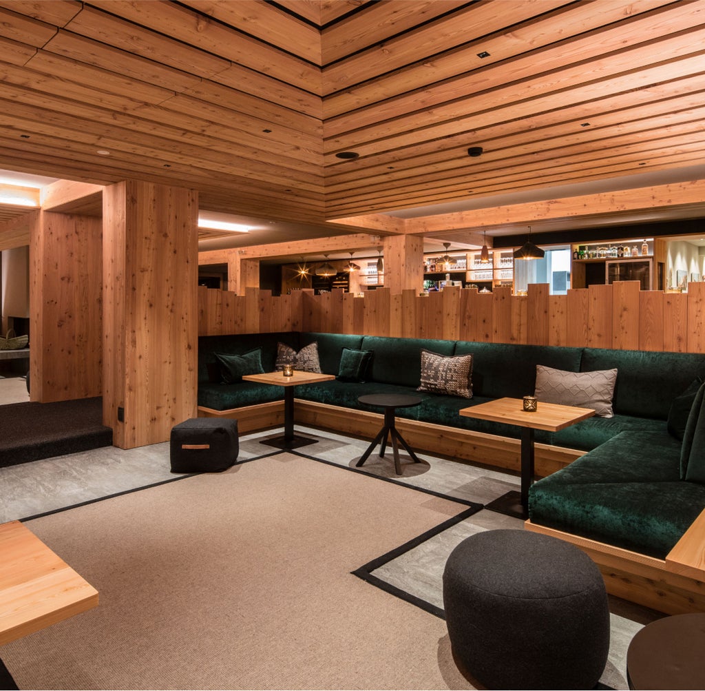 Traditional wooden alpine lodge hotel with modern glass facade nestled in snowy Dolomites mountain landscape at dusk