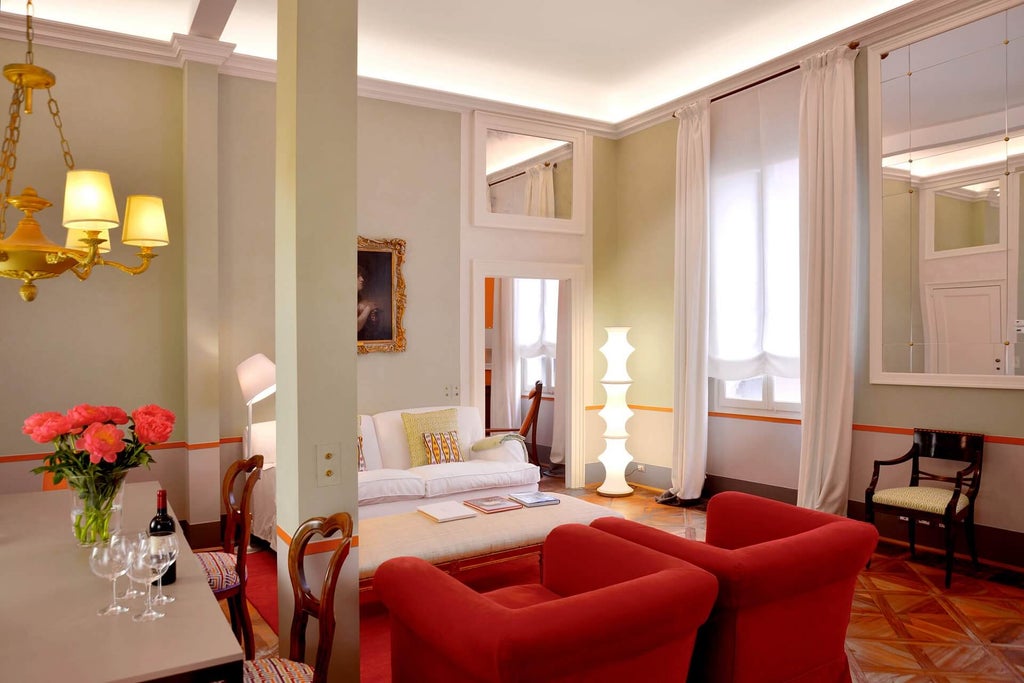 Luxurious Italian hotel room with ornate gold-framed mirrors, crystal chandelier, antique furniture, and damask wallpaper in cream and gold tones