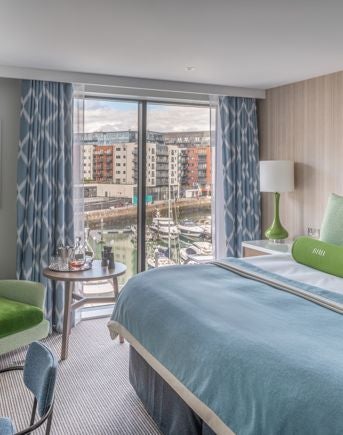 Luxurious Marina View Suite with private balcony overlooking Southampton harbour, featuring elegant contemporary decor and sweeping water landscape