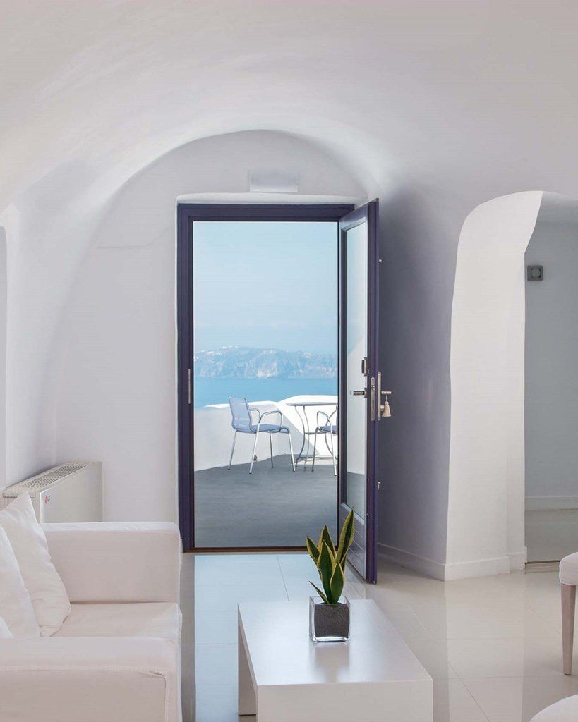 Elegant white-washed Santorini suite with private infinity pool, sweeping Aegean Sea views, minimalist luxury decor, and iconic blue-domed architecture