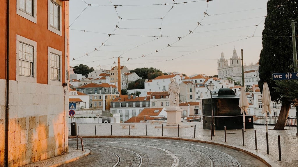 Elegant rooftop terrace in Lisbon overlooking historic red-tiled buildings and blue coastline during golden sunset light