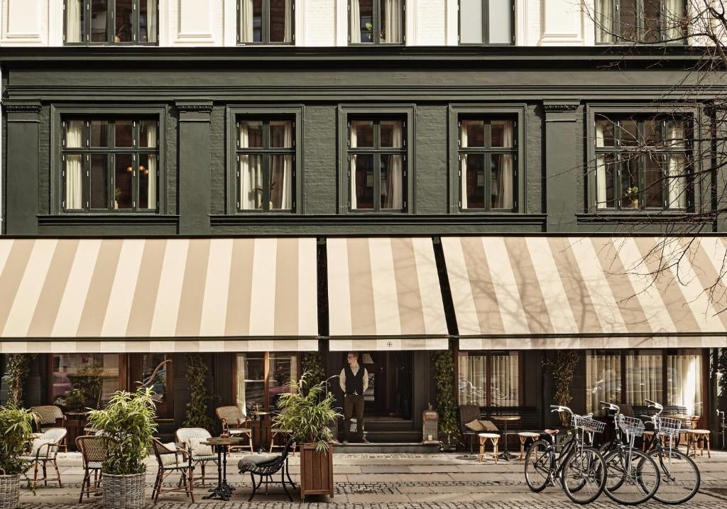 Elegant boutique hotel exterior with classic Danish architecture, featuring arched windows, ornate stonework and sophisticated entrance lighting