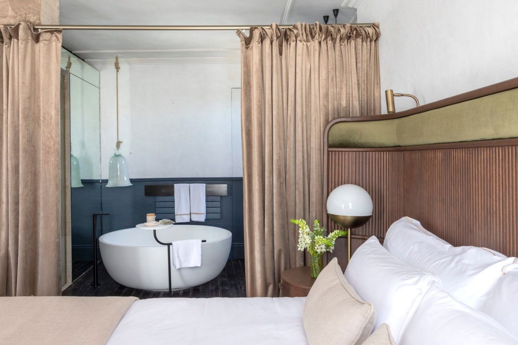 Elegant sky suite with soft neutral tones, expansive windows, plush bedding, and breathtaking views of historic Spanish architectural landscape at Can Bordoy Grand House.