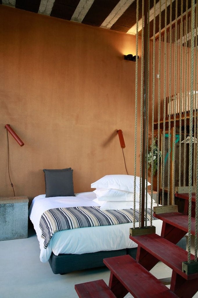 Minimalist surf-inspired bedroom with white walls, wooden accents, and ocean-view window in scenic coastal Portuguese accommodation.