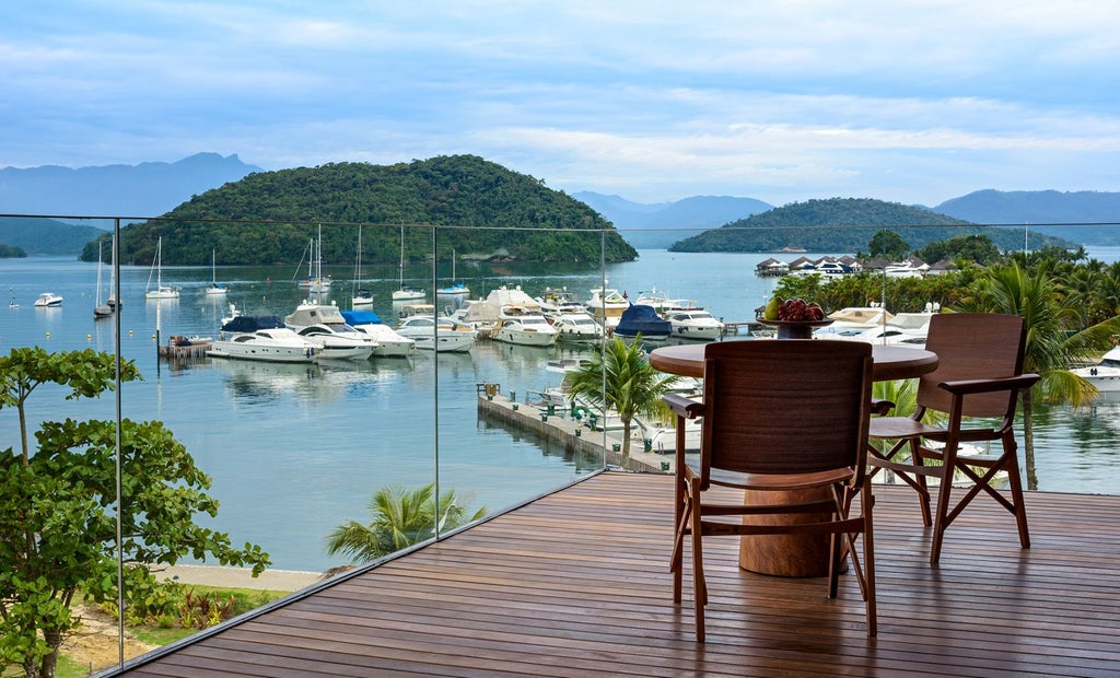 Luxurious oceanfront hotel with infinity pool overlooking tropical hills, featuring modern architecture and panoramic bay views at sunset