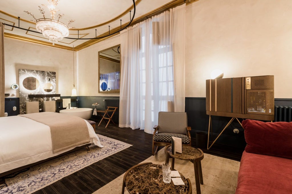 Elegant premium suite with antique wooden furnishings, soft neutral tones, plush king bed, and ornate Spanish architectural details in a luxurious historic setting