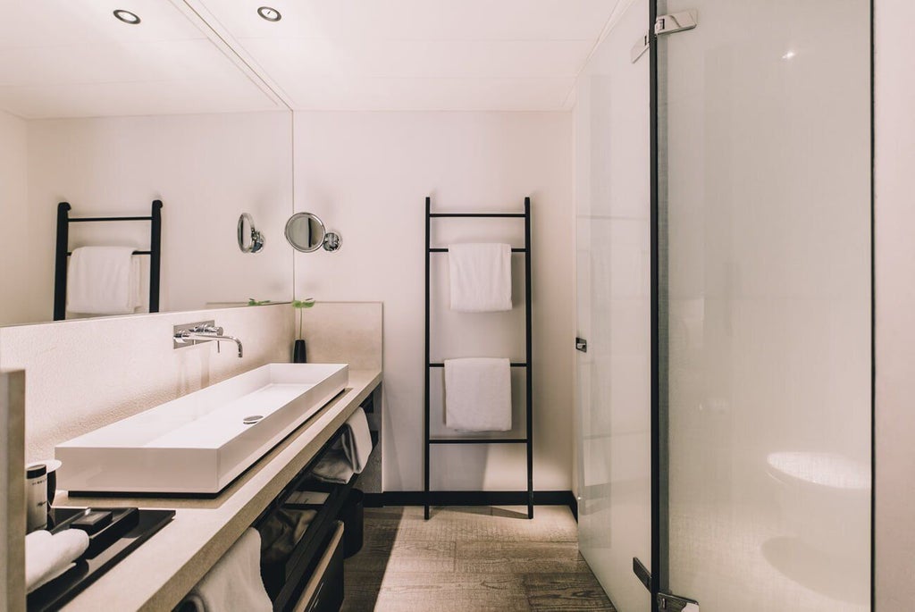 Elegant deluxe hotel room at Sant Francesc Hotel Singular in Spain, featuring minimalist design, plush white bedding, and warm wood accents with soft natural lighting