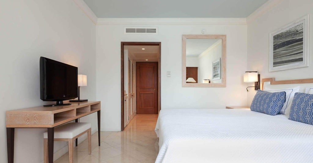 Modern luxury sea view hotel room with elegant white decor, expansive balcony, and panoramic azure Mediterranean waters stretching to the Cyprus coastline horizon