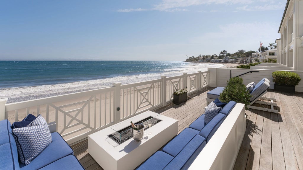 Luxurious Beach House Terrace Suite overlooking Pacific Ocean, elegant outdoor seating, wooden deck, lush coastal landscape and pristine beach horizon