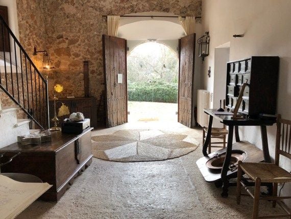 Historic stone luxury hotel nestled in Valldemossa's mountainous landscape, showcasing traditional Mallorcan architecture with rustic stone walls and terracotta roof tiles against lush green scenery.