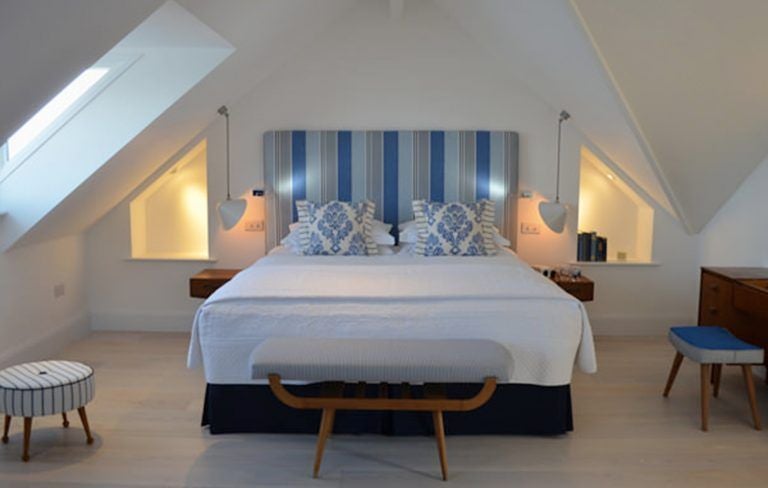 Elegant coastal bedroom at Trevose Harbour House with crisp white linens, ocean-view window, and neutral coastal-inspired decor in soft blues and grays