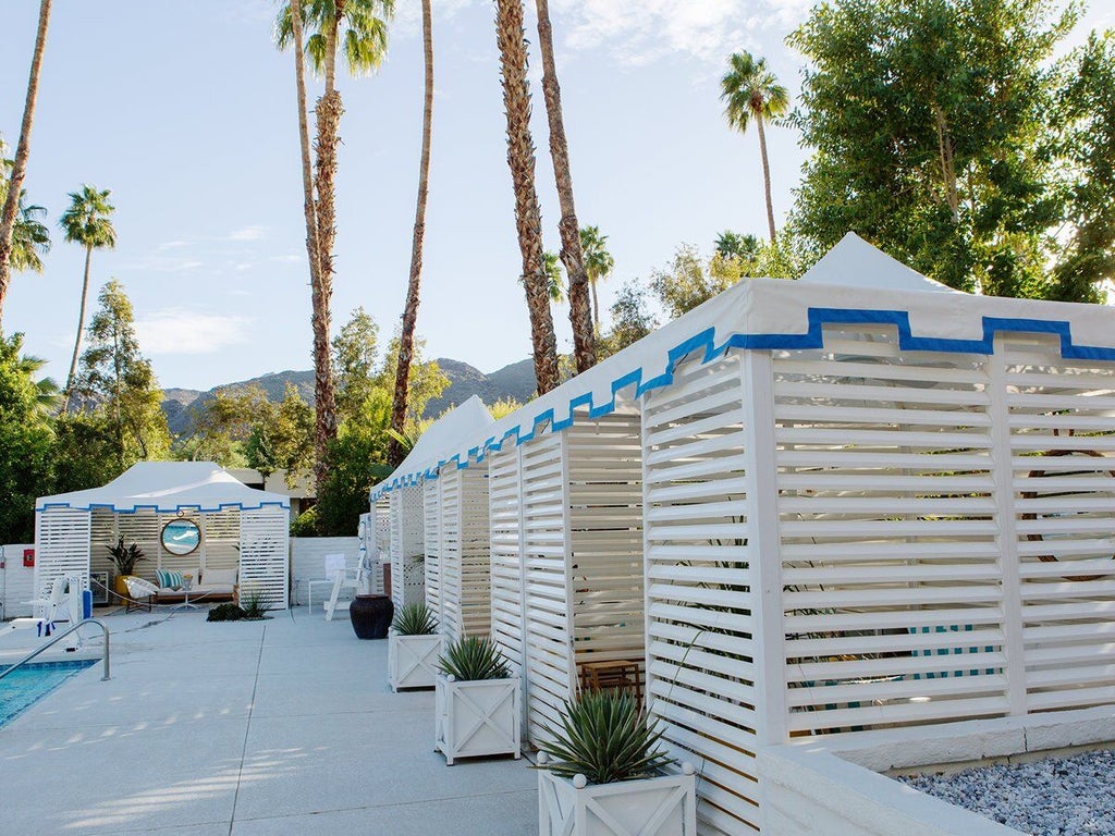 Elegant Spanish Colonial-style Parker Palm Springs hotel facade with white walls, palm trees, and manicured desert landscaping at sunset