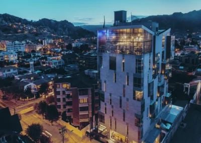 Modern luxury hotel with sleek architecture nestled in Bolivian landscape, showcasing contemporary design with clean lines and panoramic mountain views at sunset