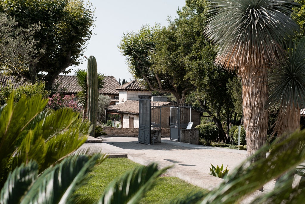 Elegant French château hotel with stone facade, manicured gardens, and reflective pool surrounded by mature cypress trees and landscaping