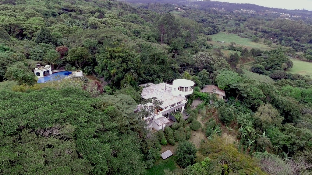 Luxurious eco-lodge nestled in Costa Rican hillside, surrounded by lush coffee plantations and tropical gardens with mountain views