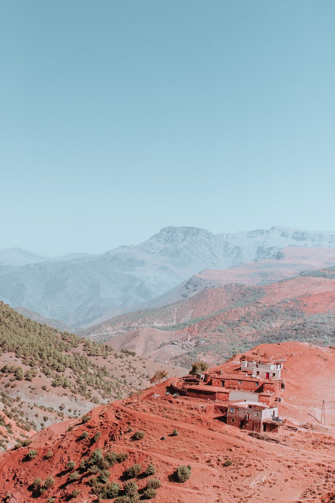 Luxurious hiking trail winding through rugged Atlas Mountains, golden sunlight illuminating Moroccan landscape with distant peaks and rocky terrain