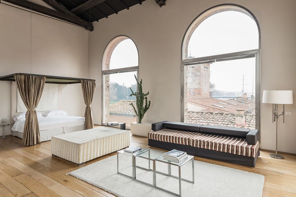 Elegant Italian loft suite with minimalist design, wooden floors, high ceilings, natural light, and contemporary furnishings in warm neutral tones