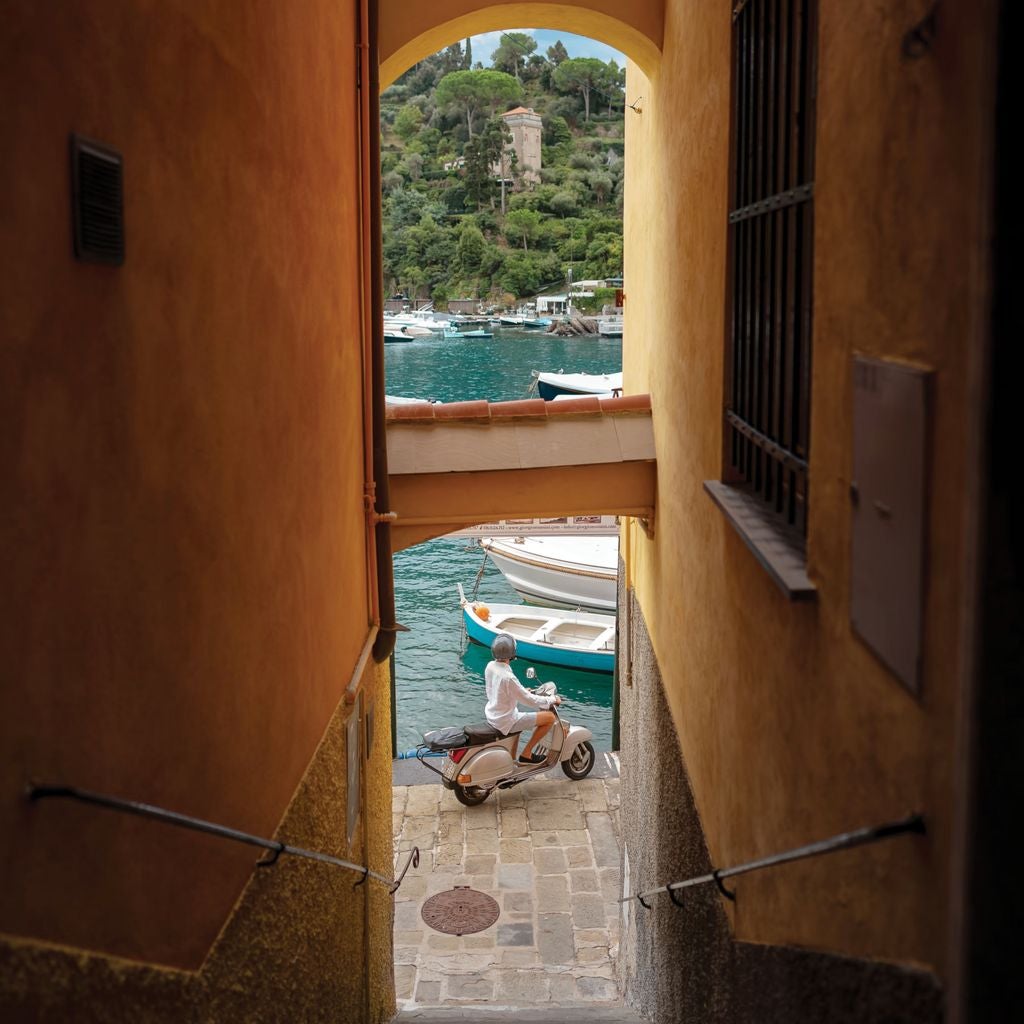 Historic colorful buildings with luxury yachts in Portofino's harbor at sunset, pastel facades reflect in Mediterranean waters