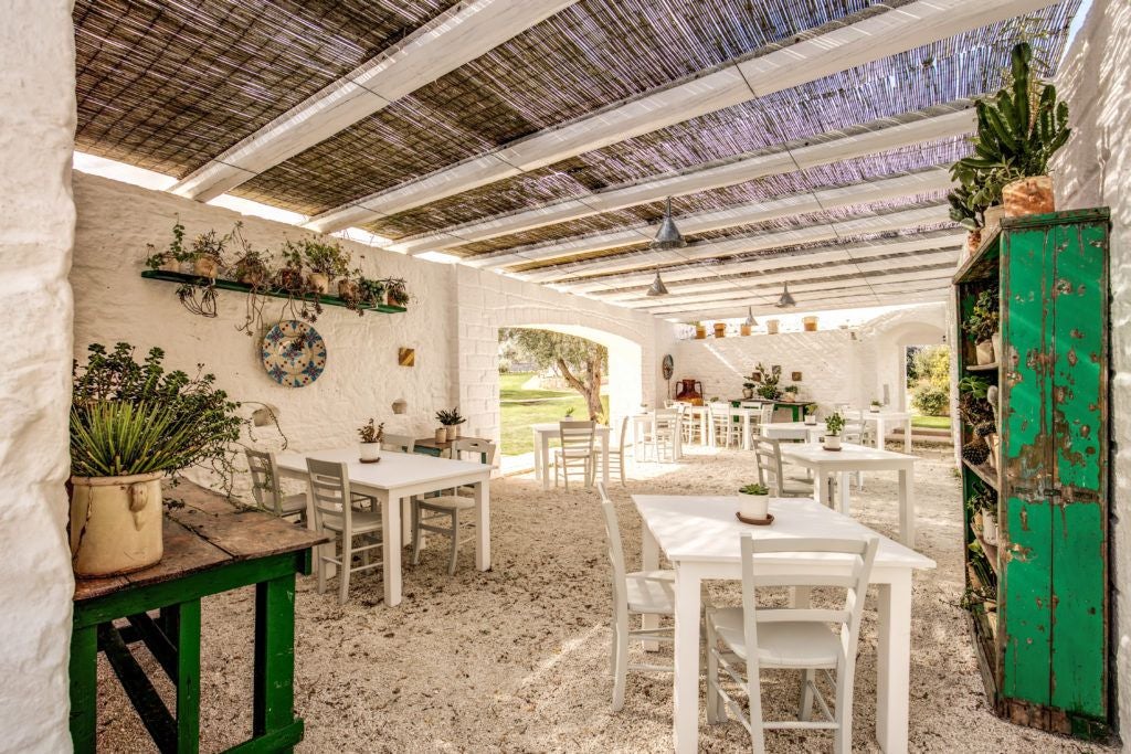 Rustic stone farmhouse nestled in Puglia's countryside, with sun-drenched limestone walls, terracotta roof, and lush olive grove surrounding luxurious traditional Italian retreat