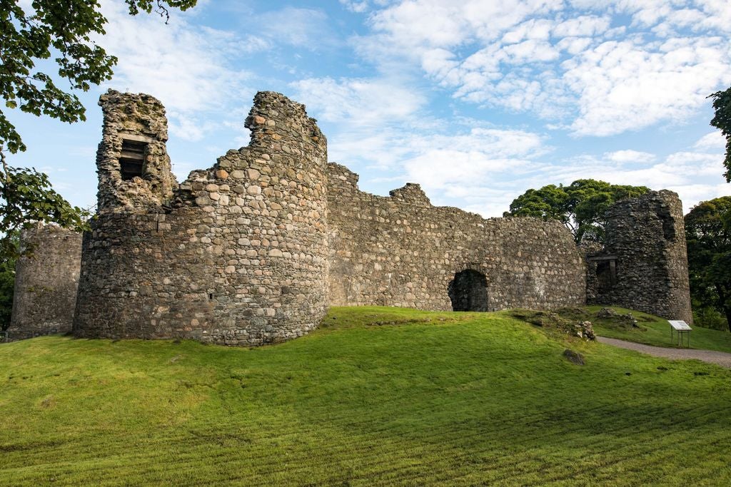 Historic Inverlochy Castle hotel nestled in Scottish Highlands, surrounded by manicured gardens and mountains, with Gothic turrets and grey stone