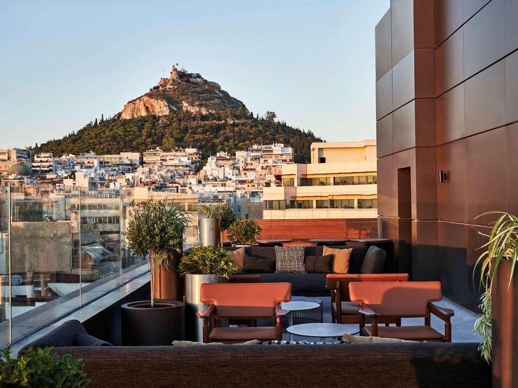 Elegant marble facade of Athens Capital Hotel with neoclassical columns, ornate balconies, and warm lighting at dusk in downtown Athens