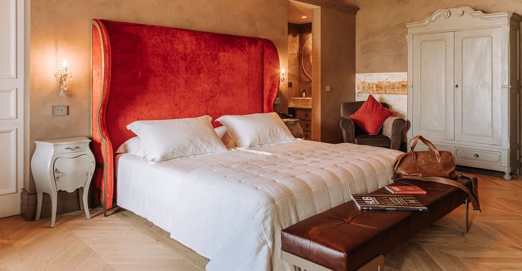 Elegant Italian superior suite with plush white bedding, ornate headboard, and soft ambient lighting in a refined boutique hotel room