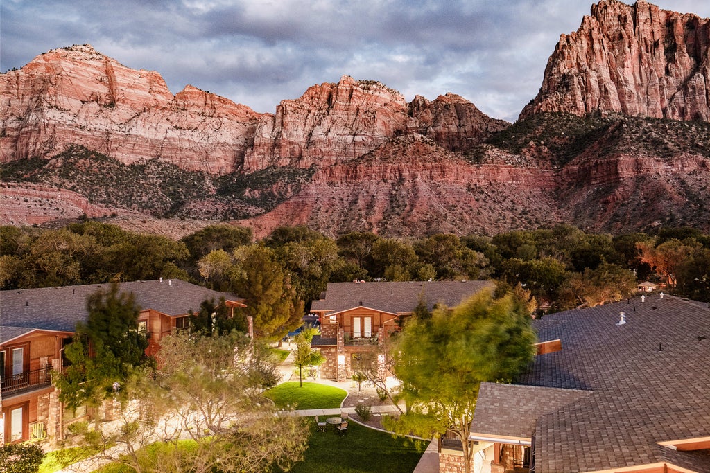 Luxurious mountain lodge with rustic stone facade, nestled against red cliffs, featuring panoramic views and upscale modern architecture