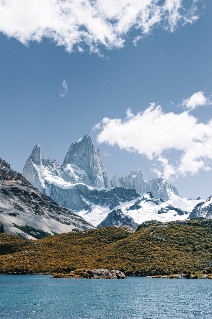 Majestic Mount Fitz Roy peak towers over El Chalten village, framed by golden sunrise light and pristine Patagonian wilderness