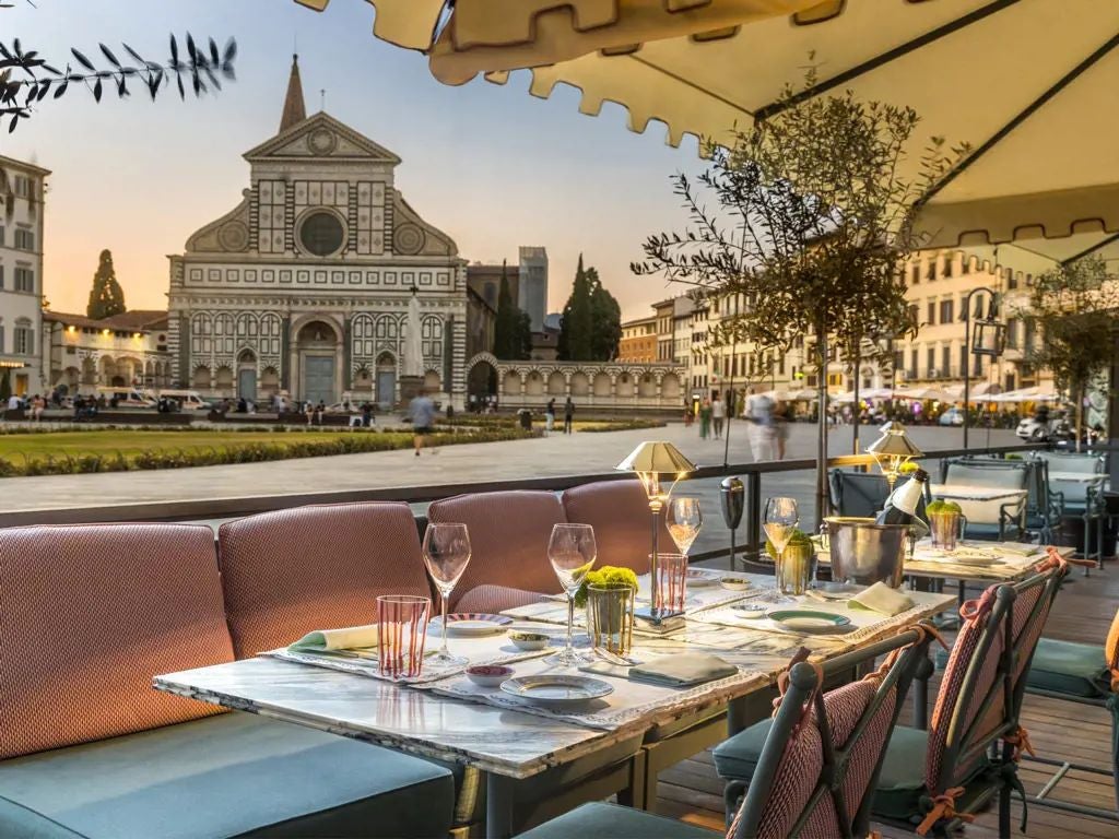 Elegant beige Florentine boutique hotel with ornate iron balconies, classic shuttered windows, and refined European architectural details