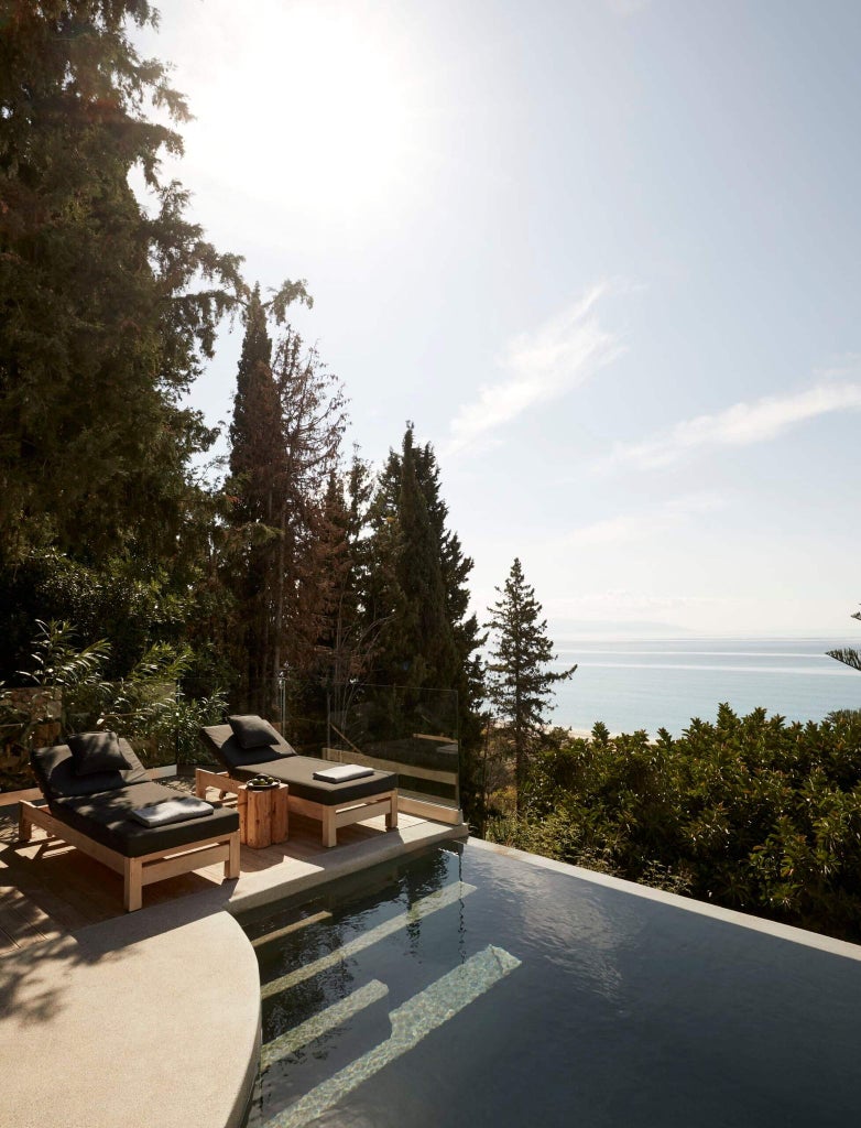 Luxurious white-walled Greek villa with minimalist design, overlooking turquoise Aegean waters, featuring sleek infinity pool and lush mediterranean vegetation